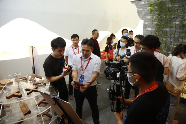 “中式原木整裝城市合伙人直播招募會”第一站在國方家居的建博會展位舉行，國方家居董事長陳新平（左三）介紹榫卯文化